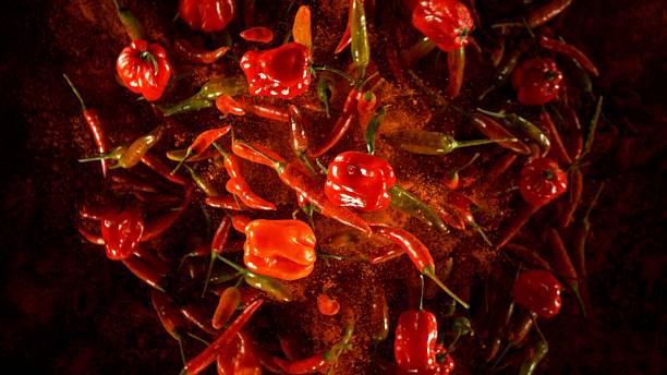 istock Group of coloured chilli peppers flying on black background. 2208090101