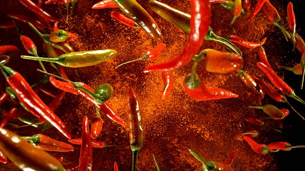 istock Hot red and green chilli peppers flying on black background. 2208090129