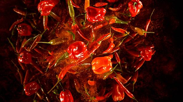 istock Group of coloured chilli peppers flying on black background. 2208090136