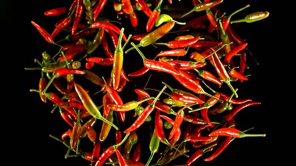istock Hot red and green chilli peppers flying on black background. 2208090375
