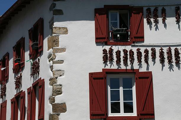 Traditional Basque house with red shutters and chili peppers drying in the sun, showcasing regional architecture and culture.