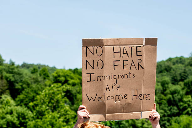 A protestor at a political rally holds a sign that reads \