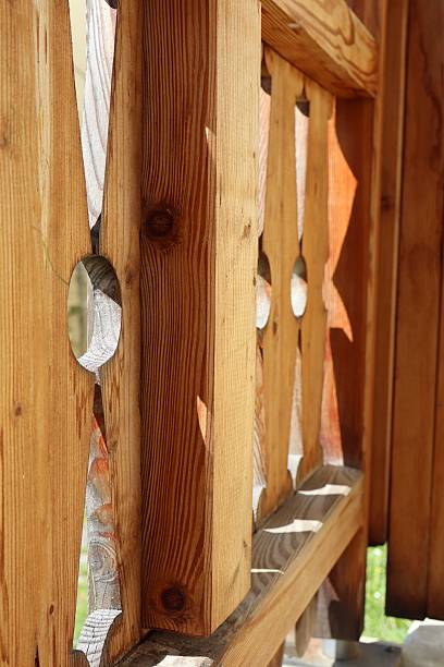 istock Close-up of a wooden railing with carved patterns and sunlight shadows. 2208094410