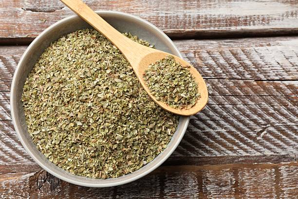 istock Dried oregano in bowl and spoon on wooden table, top view. Space for text 2208094489