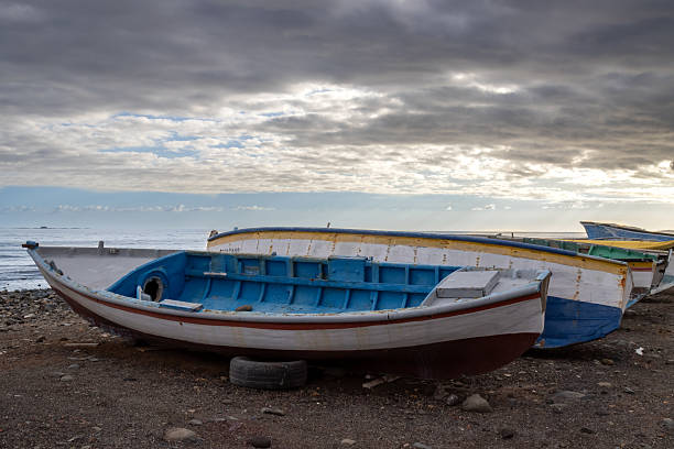 Colorful traditional fishing boats on the coast of Atlantic ocean. Sandy beach. Cloudy evening sky. Castillo del Romeral, Las Palmas, Gran Canaria, Canary Islands, Spain.