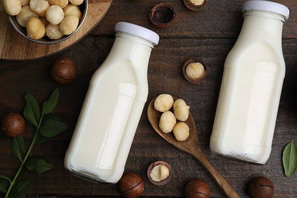 istock Bottles of macadamia milk and nuts on wooden table, flat lay 2208095711