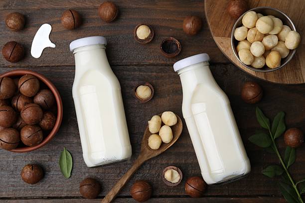 istock Bottles of macadamia milk and nuts on wooden table, flat lay 2208095737