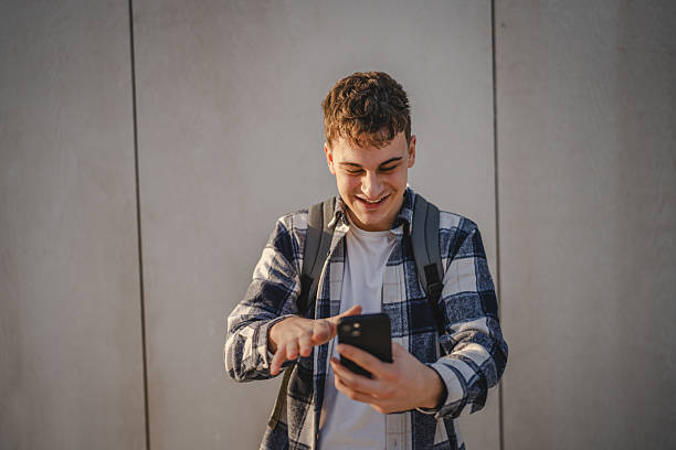 istock man student stand in front white wall have video call on mobile phone 2208098157