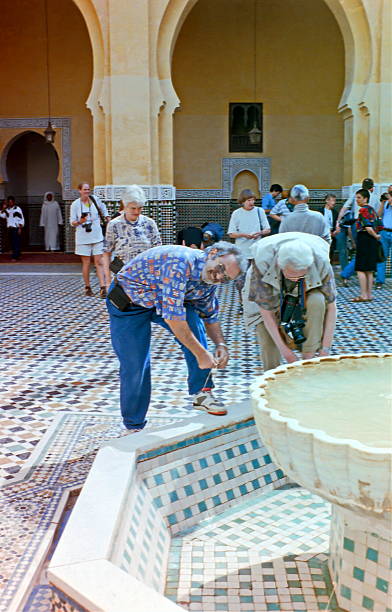 Morocco, Marrakesh - July 1997: After visiting the great Kasbah Mosque, also known as the Moulay al-Yazid Mosque, the tourists put their shoes back on.\nPlease note that this over twenty-five year old image was taken in 1997 and converted from the negative.