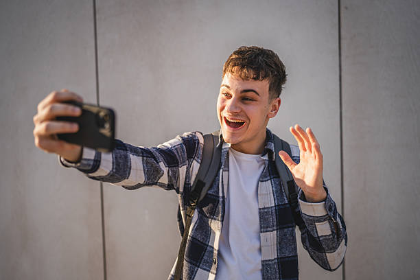istock man student stand in front white wall have video call on mobile phone 2208098510