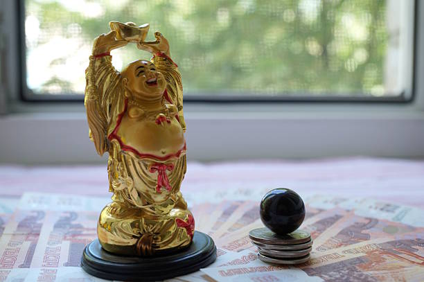 A statuette of a smiling Buddha and a tiger's eye with paper bills.
