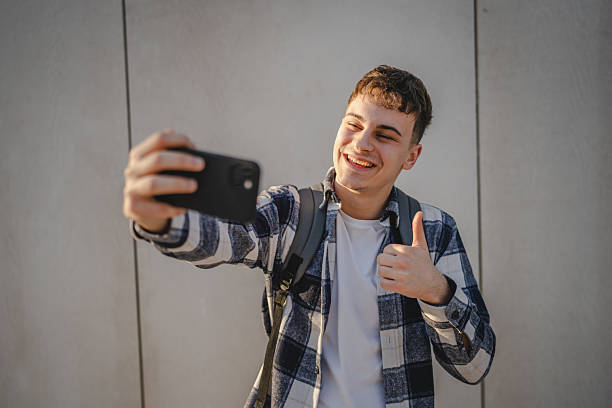 istock man student stand in front white wall have video call on mobile phone 2208098902