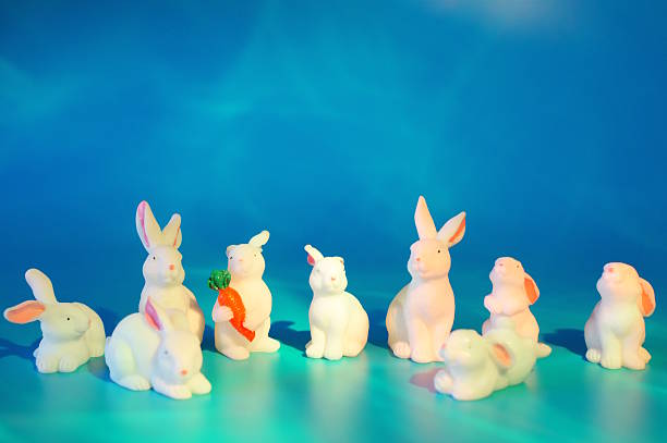 istock Toy white hares on a blue background. Animal figurines. 2208099275