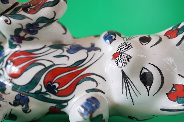 Ceramic painted cat figurine on a green background.