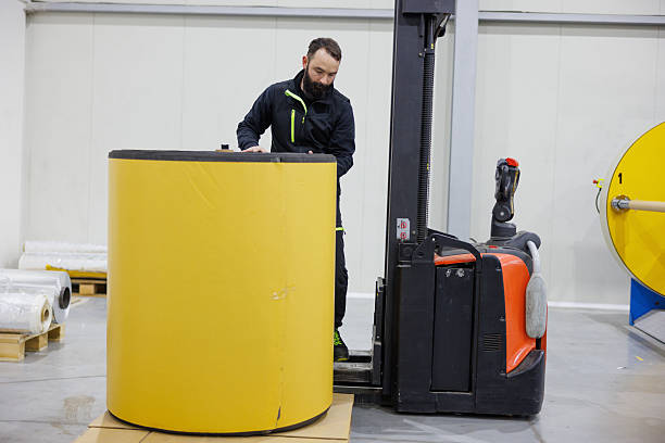 istock Man working in distribution warehouse, putting bale of electrical insulation tape on pallet 2208100919