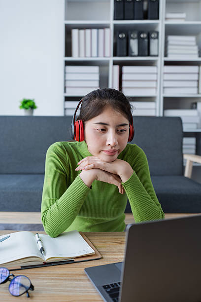 istock Woman sitting at a table using laptop in a brightly lit room while engaged in work or personal projects at home 2208101111
