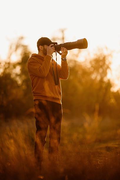 istock Photographer capturing sunset with telephoto lens. 2208101120
