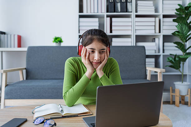 istock Woman sitting at a table using laptop in a brightly lit room while engaged in work or personal projects at home 2208101140