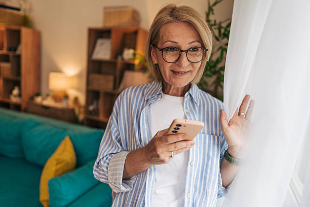 istock Smiling senior woman using smartphone at home 2208101381