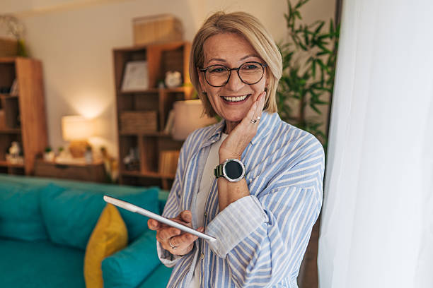 istock Senior woman using digital tablet and wearing smartwatch at home 2208101665