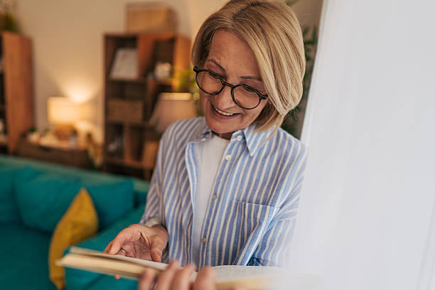 istock Smiling senior woman reading a book at home 2208101968