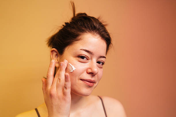 istock Young woman applying face cream 2208103606