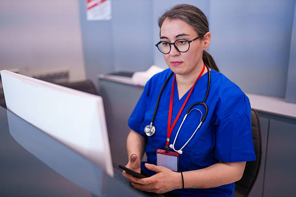 istock Healthcare Professional at Reception Desk, Using Phone and Computer 2208103815