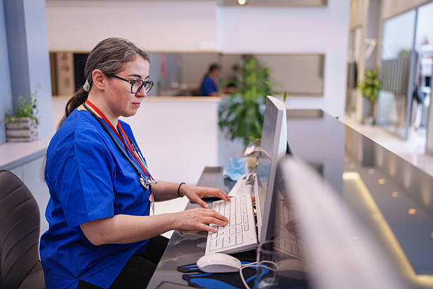Healthcare Professional Working on Computer at Reception Desk