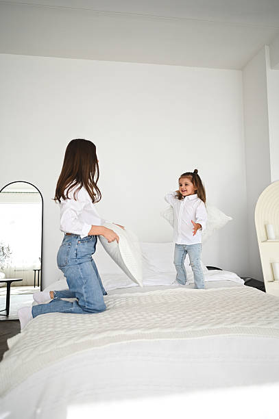 istock Mother and daughter having a pillow fight on bed 2208104019