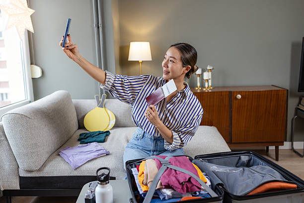 istock Young woman taking a selfie while packing clothes for a trip 2208105765