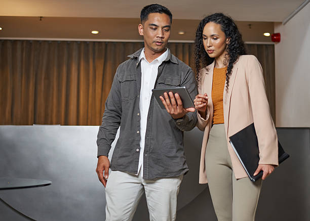 istock Two Professionals Discussing Business Plans on a Tablet in a Hotel Lobby 2208107860