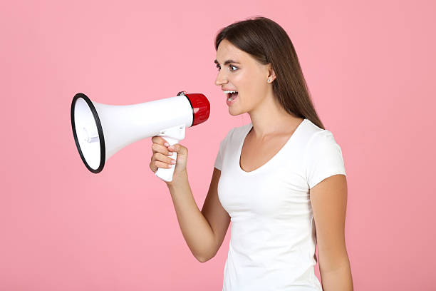 istock Young woman with megaphone on pink background 2208107876