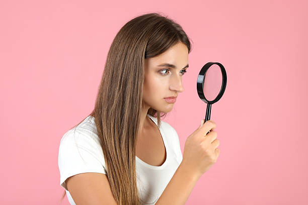 istock Young woman with magnifying glass on pink background 2208108671
