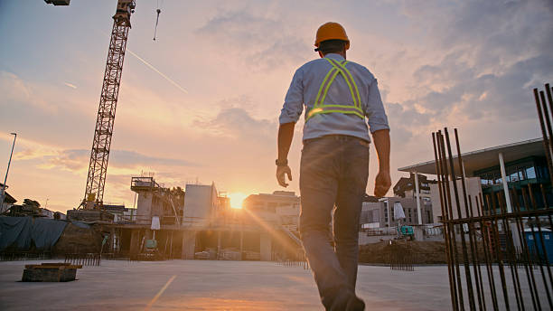 Construction Worker Walking on Site at Sunset with Reflective Vest and Hard Hat