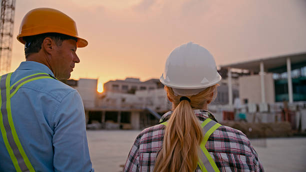 istock Construction Workers Observing Site Progress at Sunset Wearing Safety Gear 2208108945