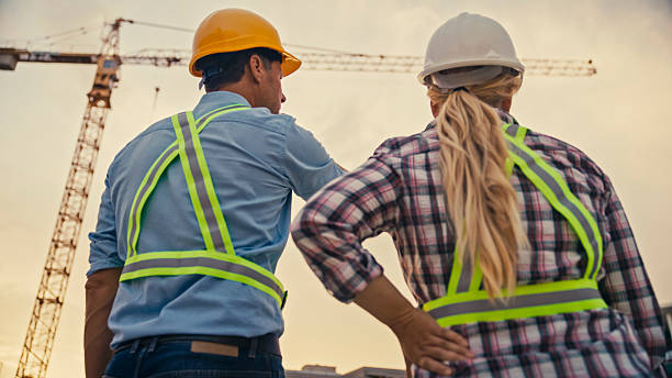 istock Male and Female Construction Workers in Safety Gear Discussing Site Progress at Sunset 2208108950