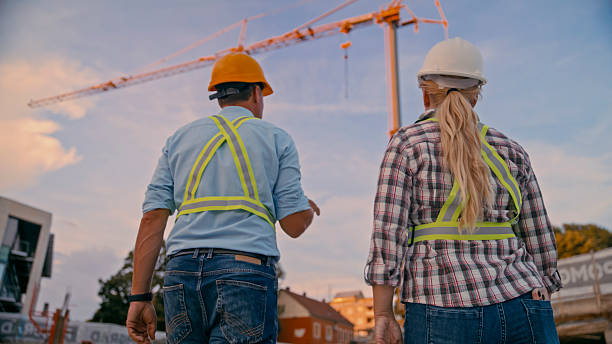 istock Construction Workers Discussing Project on a Busy Site with Tower Crane in the Background 2208108953