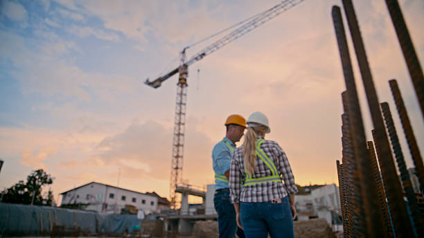 istock Construction Workers Examining Building Site at Sunset with Crane in Background 2208108965