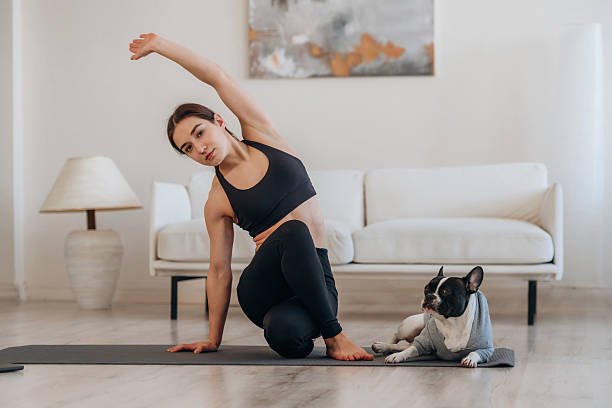 istock Active exercise. Woman with pug dog is doing yoga at home 2208109285