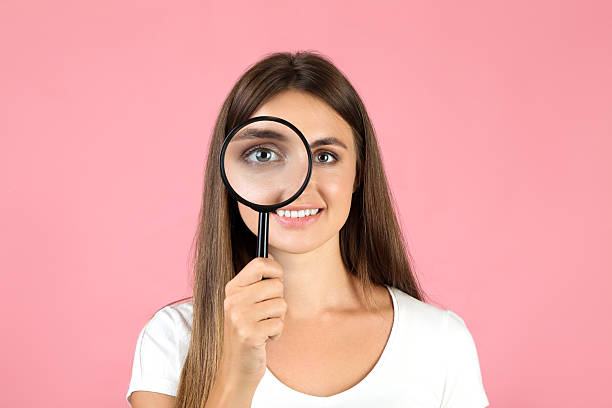 istock Young woman with magnifying glass on pink background 2208109742