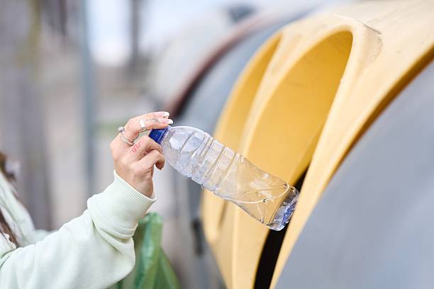 istock Woman recycling plastic bottle in yellow container 2208110579