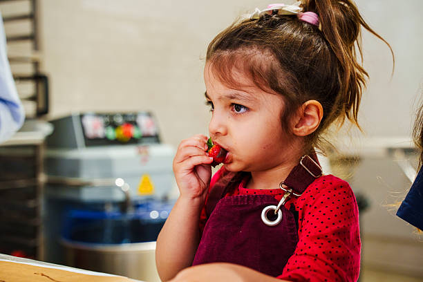 istock a child who couldn't resist eating strawberries with chocolate sauce during a chocolate workshop 2208110606