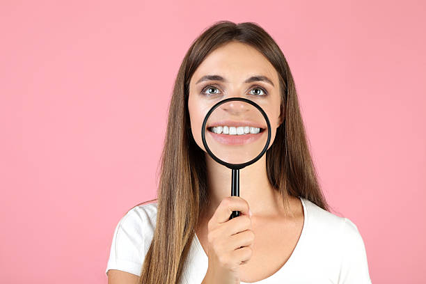 istock Young woman with magnifying glass on pink background 2208110613