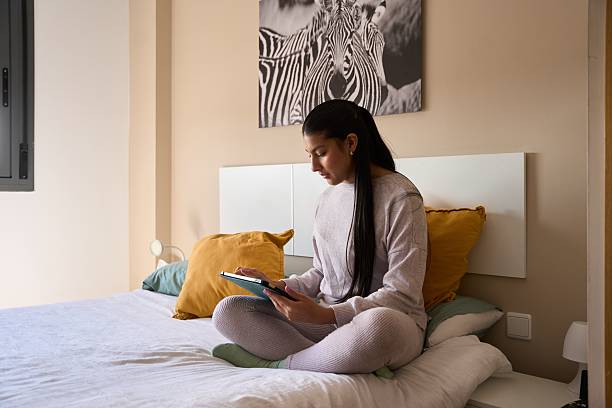 Young woman relaxing on bed using digital tablet