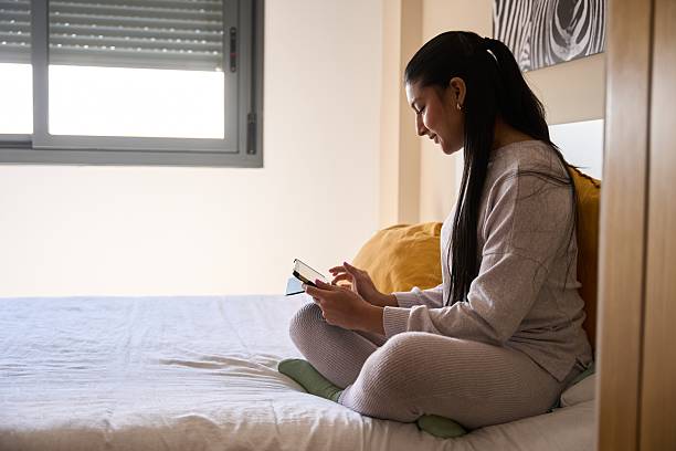 istock Young woman relaxing on bed using digital tablet in cozy bedroom 2208110631
