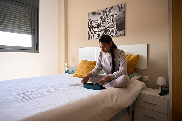 istock Young woman using digital tablet on bed in modern bedroom 2208110637