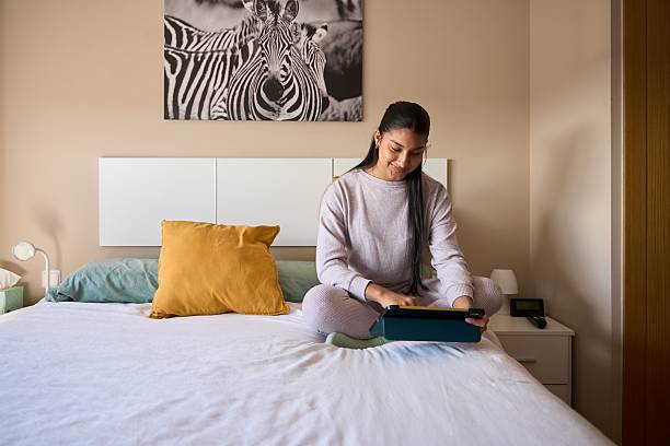 istock Young woman using digital tablet on bed in modern bedroom 2208110640