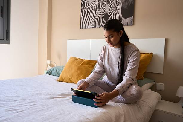 istock Young woman using digital tablet on bed in cozy bedroom 2208110642