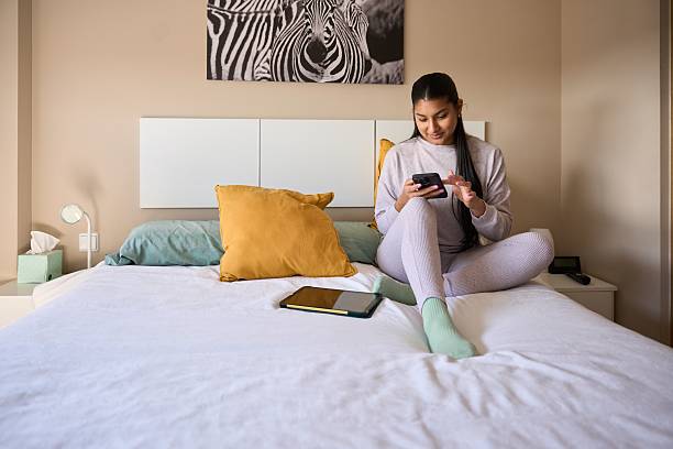 istock Young woman using smartphone on bed in modern bedroom 2208110671