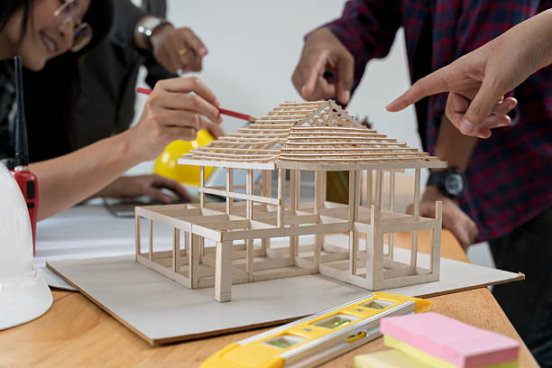 istock Group of an architect working and discussing about an architecture model together with shop drawing paper on table in office 2208110864
